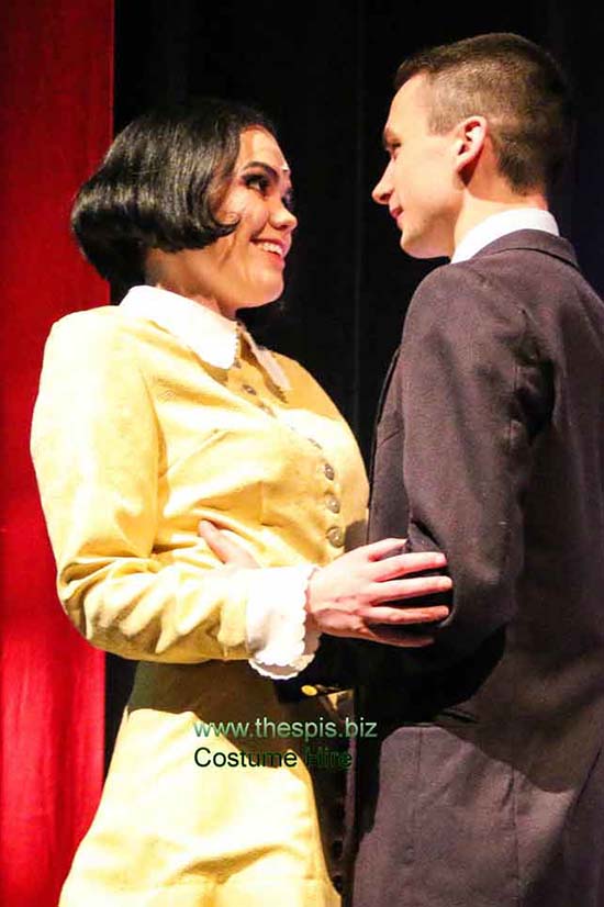 Wednesday Addams wearing stunning bright yellow short period dress, holding onto Lucas.